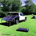 Ein weißer Pickup-Truck mit angebrachten Solarmodulen, der unter einem klaren Himmel auf einer Wiese in der Nähe eines Campingzelts geparkt ist.