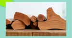 Mehrere gespaltene Brennholzscheite sind horizontal auf einer Holzfläche gestapelt und werden in einer Nahaufnahme aus seitlichem Blickwinkel vor einem hellen Hintergrund gezeigt – perfekt bearbeitet mit hochwertigen Werkzeugen von bewährten Marken wie Husqvarna oder Stihl.