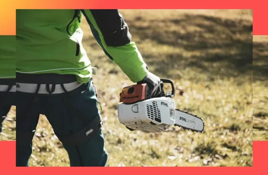 Eine Person in grüner und schwarzer Kleidung hält im Freien auf dem Rasen eine STIHL-Kettensäge in der Hand, während das Sonnenlicht Schatten wirft; sie scheint bereit zu sein, eine Akku-Kettensäge Profi auf Herz und Nieren zu prüfen.