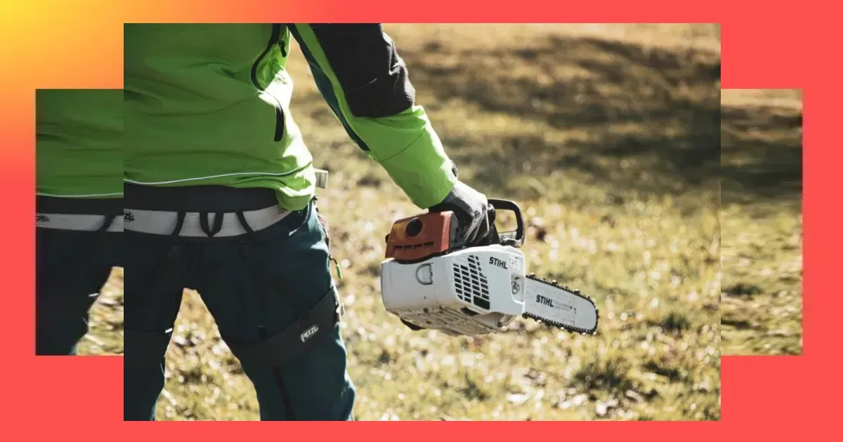 Eine Person in grüner und schwarzer Kleidung hält im Freien auf dem Rasen eine STIHL-Kettensäge in der Hand, während das Sonnenlicht Schatten wirft; sie scheint bereit zu sein, eine Akku-Kettensäge Profi auf Herz und Nieren zu prüfen.
